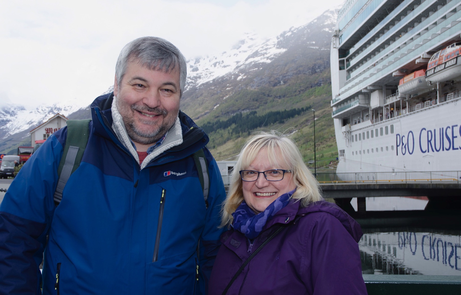 Paul and Rachel ashore in a Norwegian fjord, with the ship moored behind them